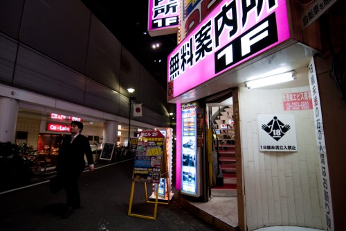 An adults-only sign decorates a doorway across from Shibuya station. An adults-only sign decorates a doorway across from Shibuya station.