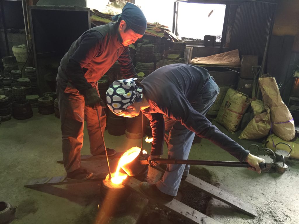 It takes two craftsmen to pour the iron into the mold